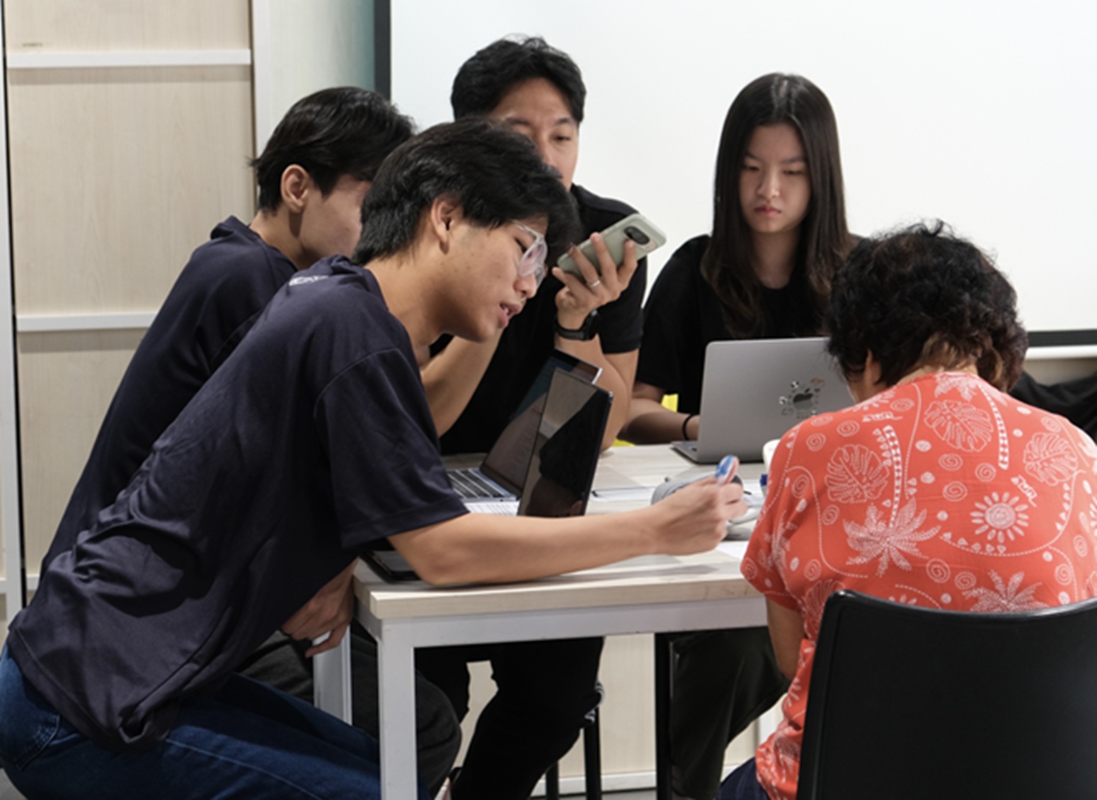 Darin Koay (Y1) explaining to a client how to take her medications at the end of the medication review session, alongside Toh Jia Jun (Y1), Wong Wei Ting (Y3), Phuan Yun Xi (Y3, not in frame) and pharmacist mentor, Mr Chia Ming Tjong.